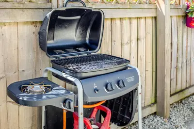a grill sitting next to a wooden fence at 19 Cormorant Drive The Annexe in St Austell