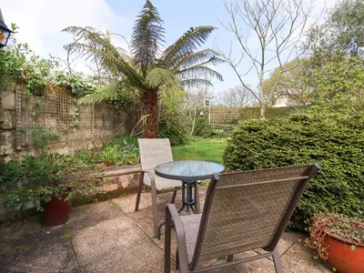 a patio with a table and chairs and a palm tree at The Ark Cottage in Par