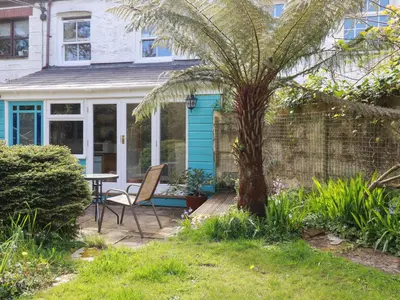 a house with a palm tree and a table at The Ark Cottage in Par