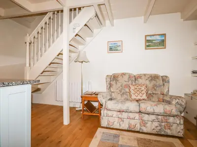 a living room with a chair and a staircase at The Ark Cottage in Par