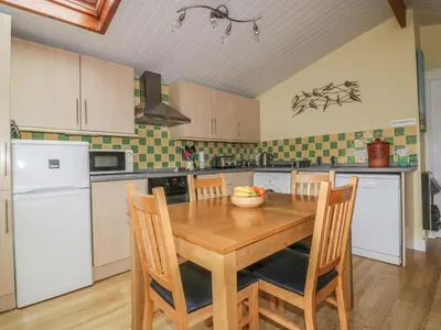 a kitchen with a wooden table and chairs at Tiggy Winkle in St Merryn