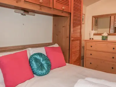 a bedroom with a bed with red and green pillows at Tiggy Winkle in St Merryn