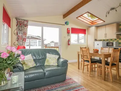 a living room with a leather couch and a table at Tiggy Winkle in St Merryn