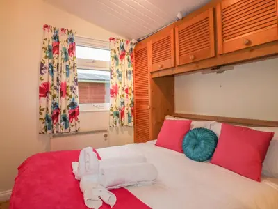 a bedroom with a large white bed with red pillows at Tiggy Winkle in St Merryn
