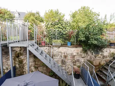 a staircase in a garden with a table and an umbrella at The Mackerel in Charlestown
