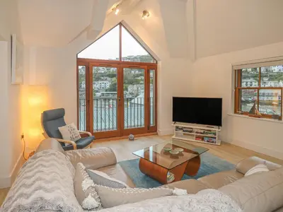 a living room with a couch and a tv at The Creekside in Looe