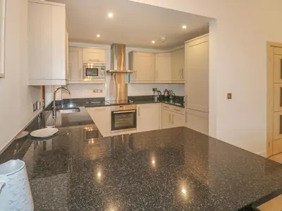a kitchen with white cabinets and a black counter top at The Creekside in Looe