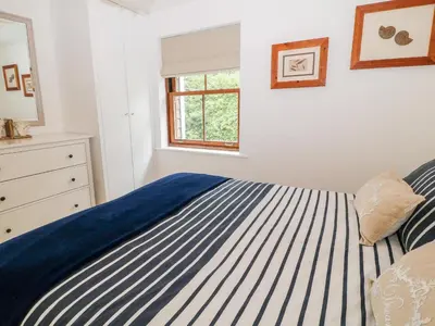 a white bedroom with a blue and white striped bed at The Creekside in Looe
