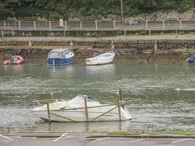 three boats are docked in a body of water at The Creekside in Looe