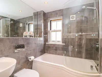 a bathroom with a tub and a toilet and a sink at The Creekside in Looe