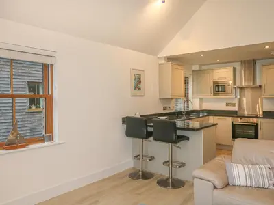 a kitchen and living room with a couch and a table at The Creekside in Looe