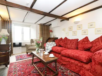 a living room with a red couch and a table at 13 Castle Hill in Lostwithiel