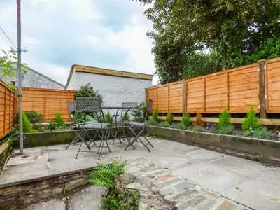 a patio with a table and chairs and a fence at 13 Castle Hill in Lostwithiel