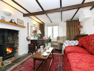 a living room with a red couch and a fireplace at 13 Castle Hill in Lostwithiel