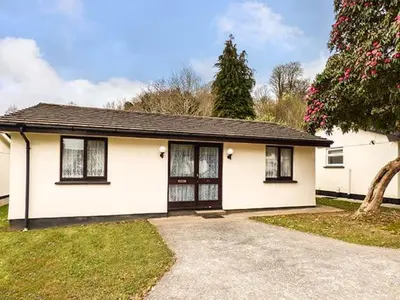 a white house with black windows and a driveway at Chy Lowenna in Saint Cleer