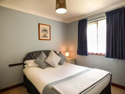 a bedroom with a large bed with blue curtains at Chy Lowenna in Saint Cleer