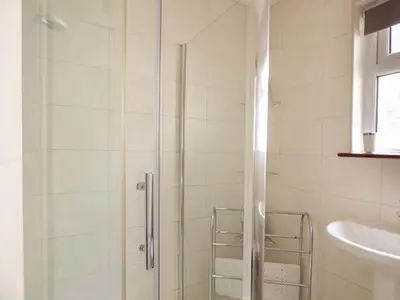 a shower with a glass door next to a sink at Chy Lowenna in Saint Cleer