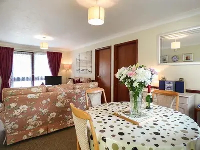 a living room with a table with a vase of flowers at Chy Lowenna in Saint Cleer
