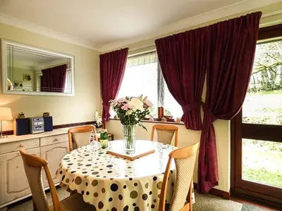a dining room table with a vase of flowers on it at Chy Lowenna in Saint Cleer