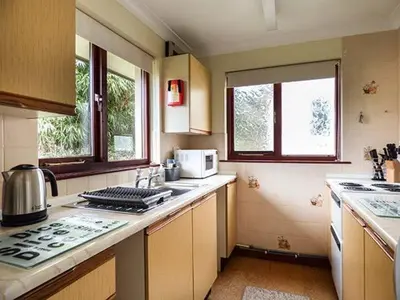 a kitchen with a stove top oven next to two windows at Chy Lowenna in Saint Cleer