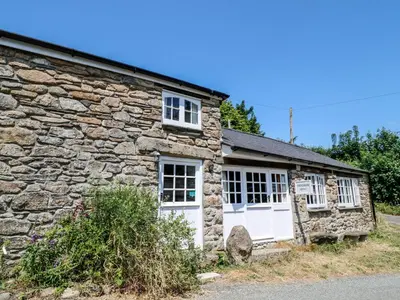 an old stone cottage with white doors and windows at Treverbyn Smithy in Saint Neot