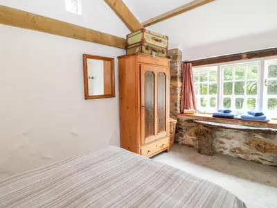 a bedroom with a bed and a wooden cabinet at Treverbyn Smithy in Saint Neot