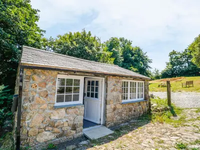 a small stone building with a door and windows at Treverbyn Smithy in Saint Neot