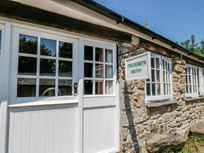 a white garage door and a sign on a stone building at Treverbyn Smithy in Saint Neot