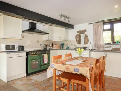 a kitchen with a table and a green stove top oven at Foxes in Lanivet