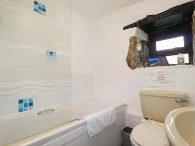 a white bathroom with a toilet and a sink at Foxes in Lanivet