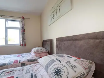 a bedroom with a bed and a headboard and a window at Merlin's Retreat in Tintagel