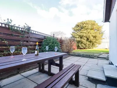 a wooden picnic table with wine glasses on a patio at Merlin's Retreat in Tintagel