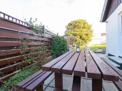 a wooden picnic table with two wine glasses on it at Merlin's Retreat in Tintagel