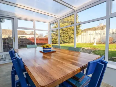 a dining room with a wooden table and blue chairs at Merlin's Retreat in Tintagel