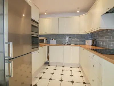 a kitchen with white cabinets and a tiled floor at Apartment 1, Trearren in St. Agnes