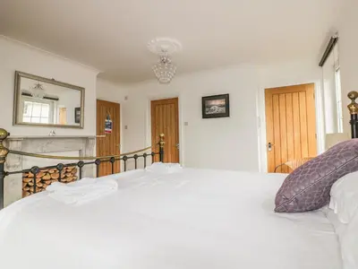 a bedroom with a white bed and a chandelier at Apartment 1, Trearren in St. Agnes