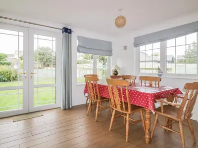 a dining room with a table and chairs and windows at Apartment 1, Trearren in St. Agnes