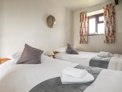 a bedroom with two beds and a window at Kestrel Corner in Lanivet