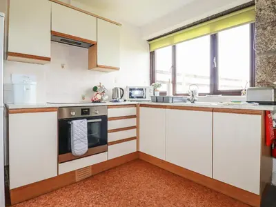 a kitchen with white cabinets and a stove at Kestrel Corner in Lanivet