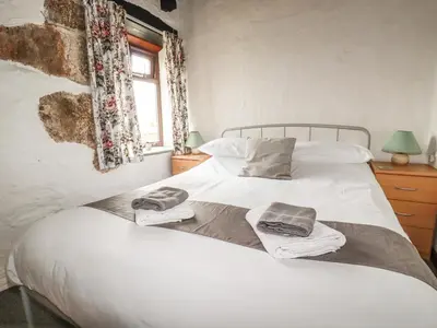 a bedroom with a white bed with towels on it at Badgers Sett in Lanivet