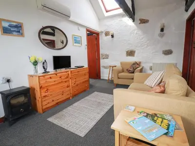 a living room with a couch and a tv and a stove at Badgers Sett in Lanivet