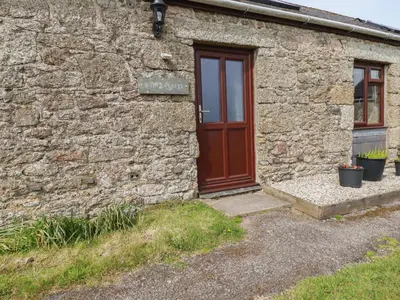 a brick building with a red door and two plants at Badgers Sett in Lanivet