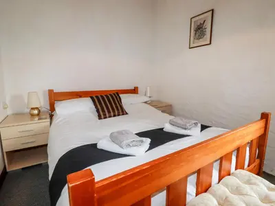 a bedroom with a wooden bed with towels on it at Ravens Croft in Lanivet