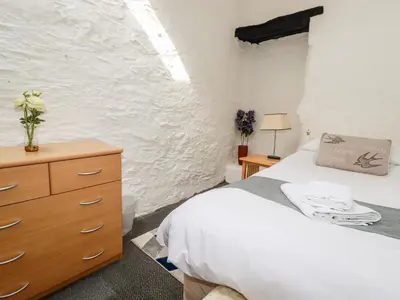 a bedroom with a bed and a wooden dresser at Ravens Croft in Lanivet