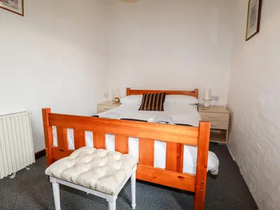 a bedroom with a wooden bed and a chair at Ravens Croft in Lanivet