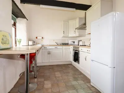 a kitchen with white cabinets and a white refrigerator at Ravens Croft in Lanivet