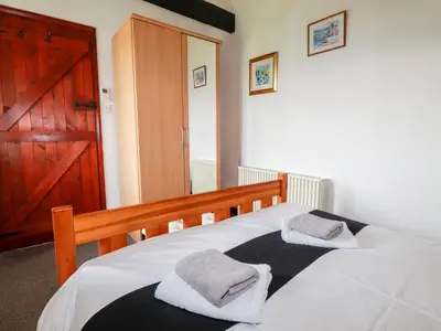 a bedroom with a bed with two towels on it at Ravens Croft in Lanivet