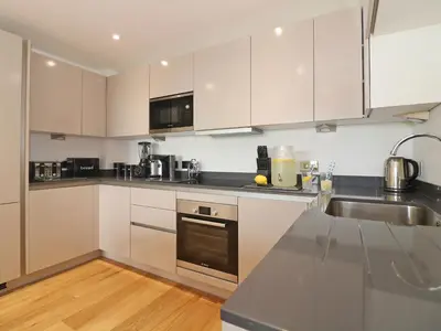 a kitchen with white cabinets and stainless steel appliances at Saltwater, One Lusty Glaze in Newquay