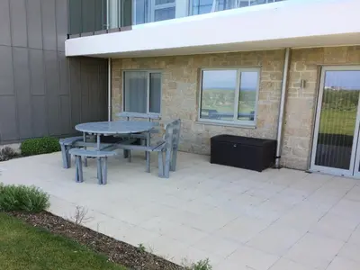 a patio with a table and chairs next to a building at Saltwater, One Lusty Glaze in Newquay