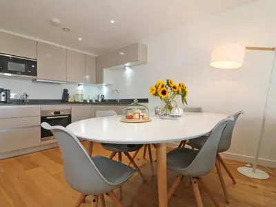 a kitchen with a white table and chairs at Saltwater, One Lusty Glaze in Newquay